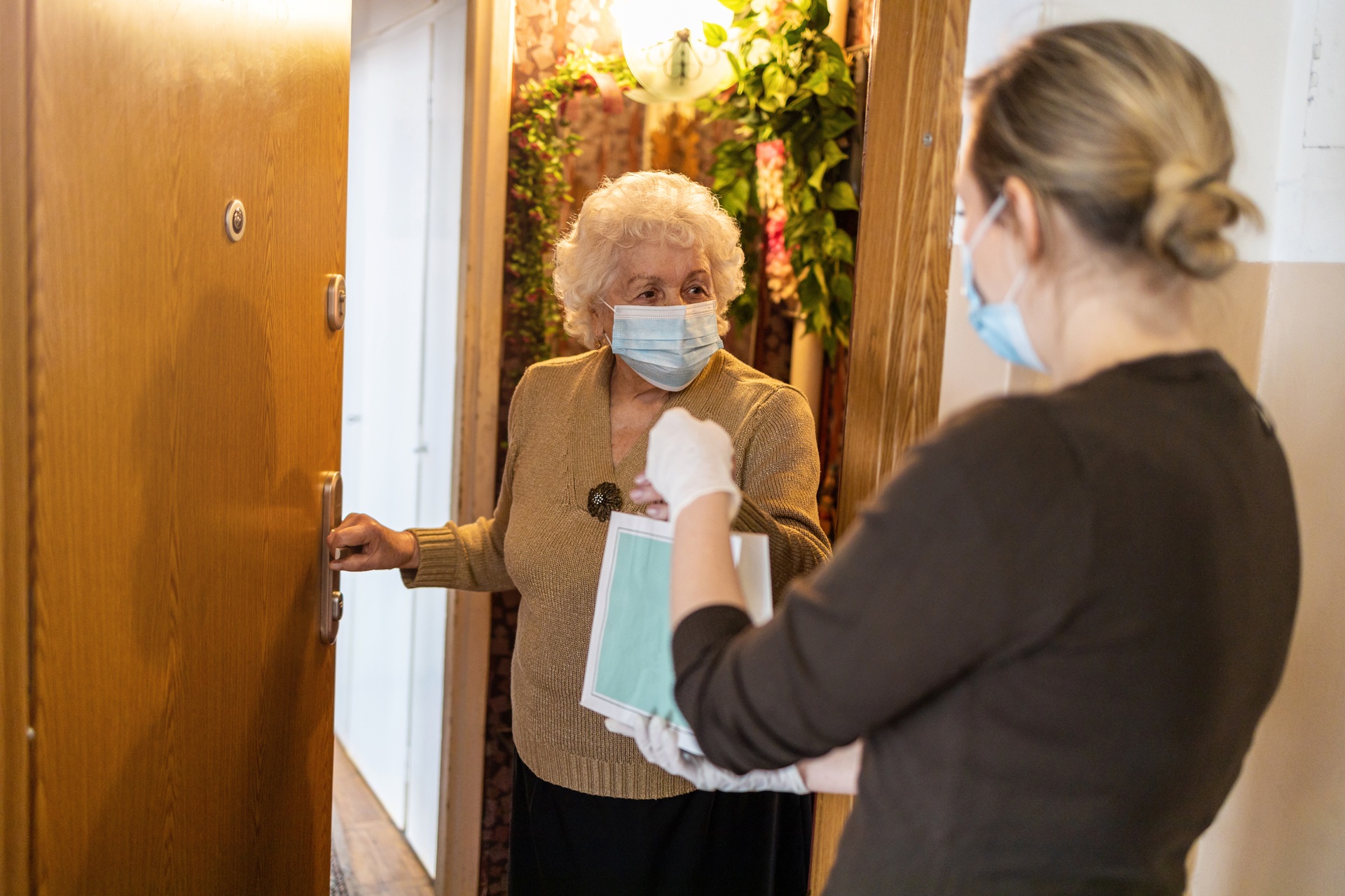 Female,Volunteer,Delivering,Bags,With,Shopping,To,Elderly,Woman,During